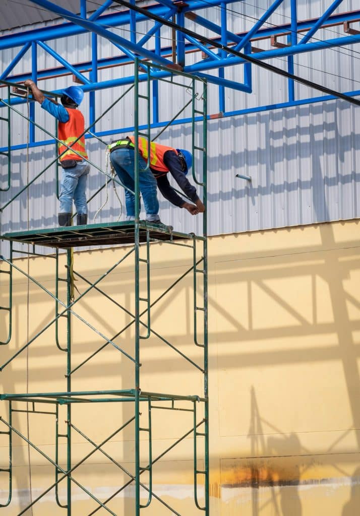 2 construction workers installing high scaffolding for construction of industrial building structure